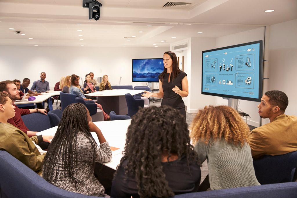Teacher using interactive displays and PTZ camera in a college classroom.
